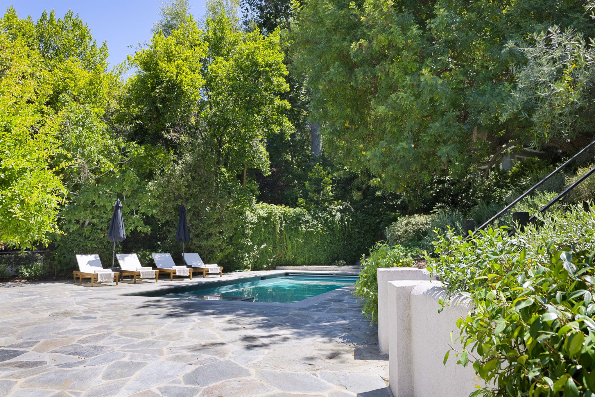 A pool and flagstone patio framed by mature greenery in Fryman Estates, Studio City.