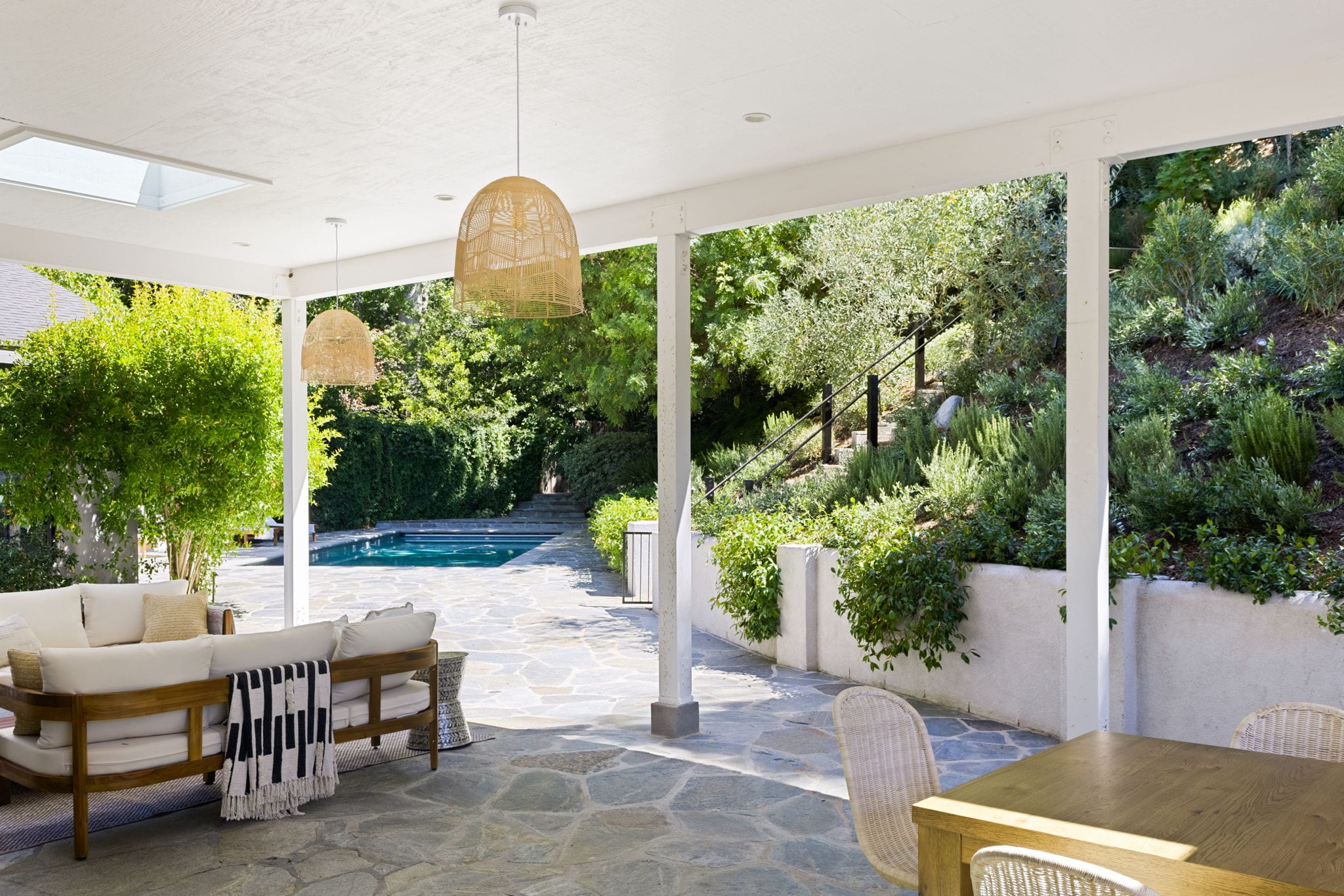 A covered patio opening to a pool and hillside garden in Fryman Estates, Studio City.